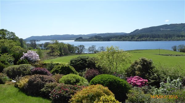 self-catering cottage garden in bloom, fields and loch in scotland